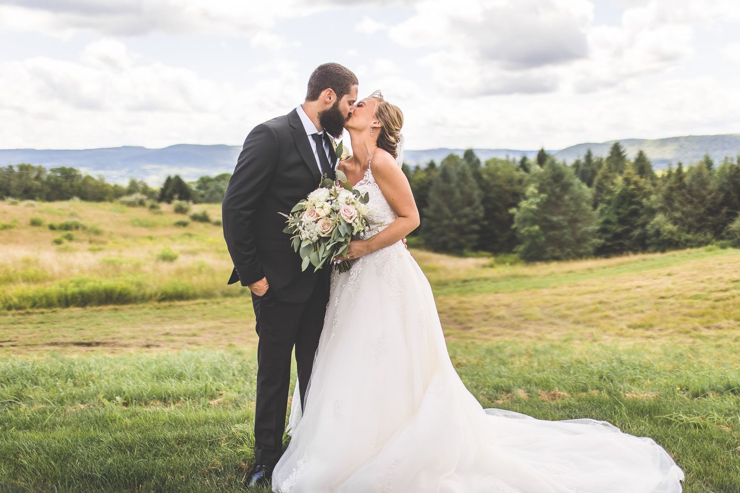Newlyweds share a romantic moment in a mountain meadow with flowing white wedding dress.