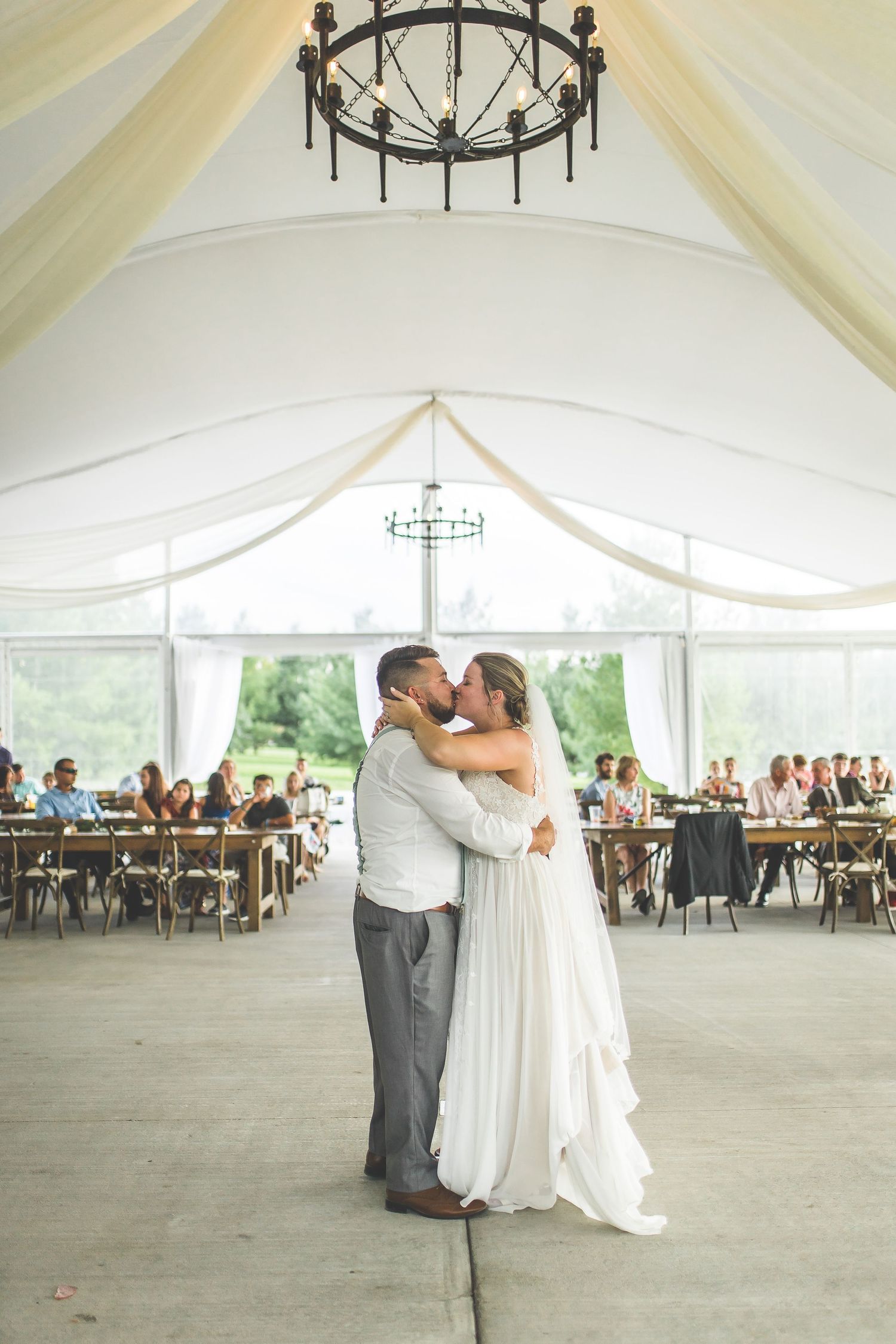 Wedding reception venue with elegant black chandeliers and flowing white tent draping.