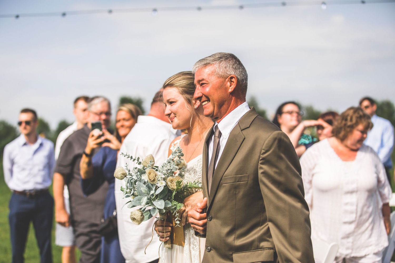 Wedding party celebrating with joyful embraces during an outdoor countryside celebration.