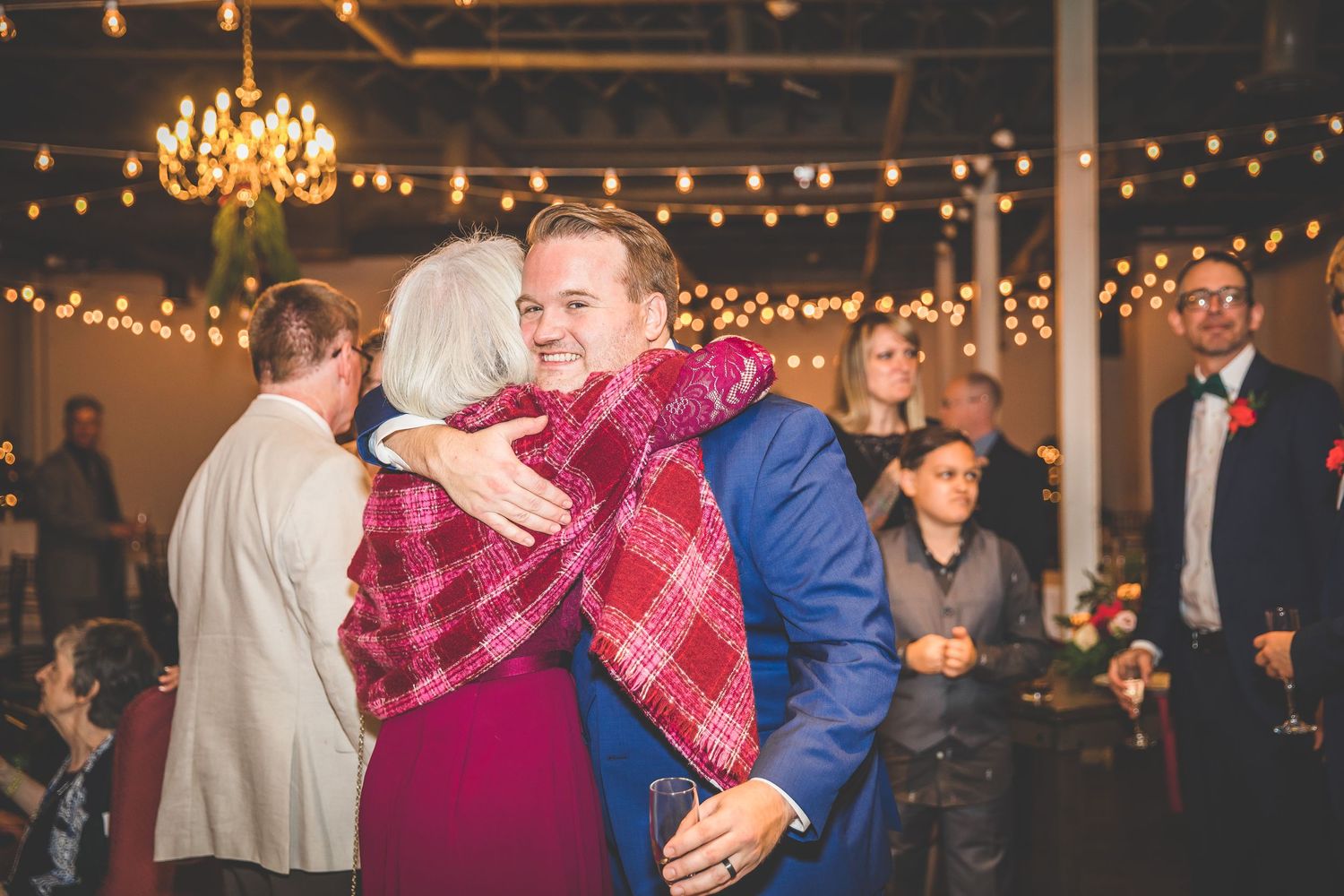 Wedding celebration with string lights and chandelier creating a warm ambiance for dancing.