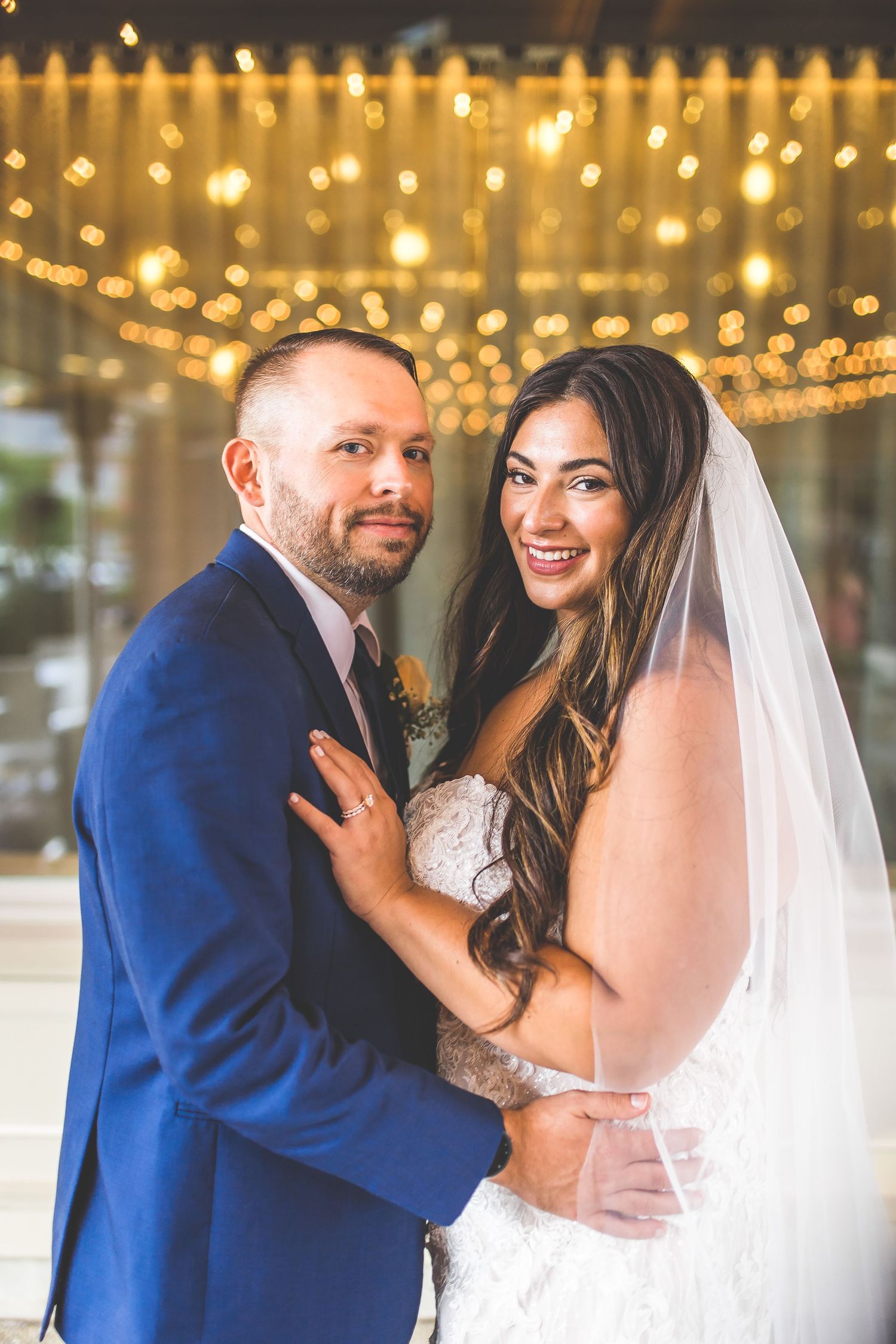 Intimate wedding couple portraits with string light backdrop and blue suit details.