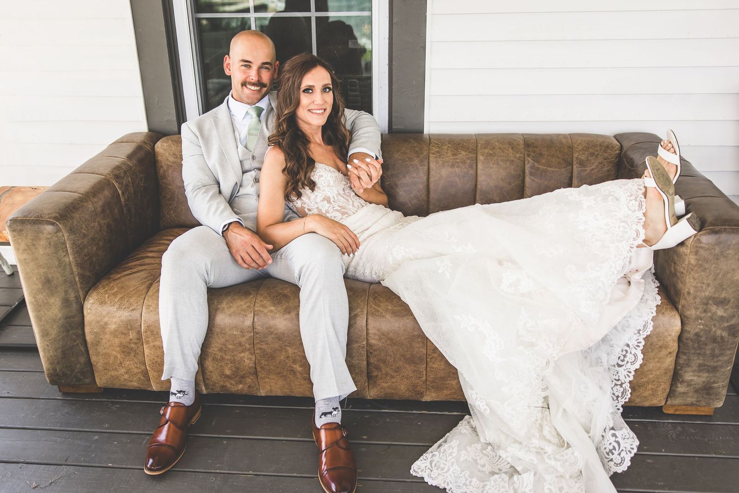 A couple relaxes together on a vintage brown leather couch.
