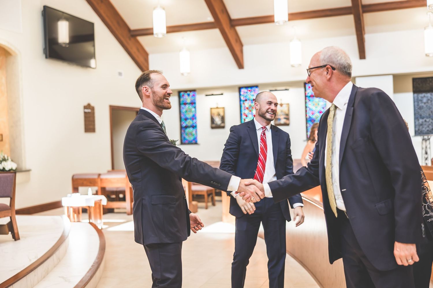 Candid shots of wedding party members interacting in a church with exposed wooden ceiling beams.