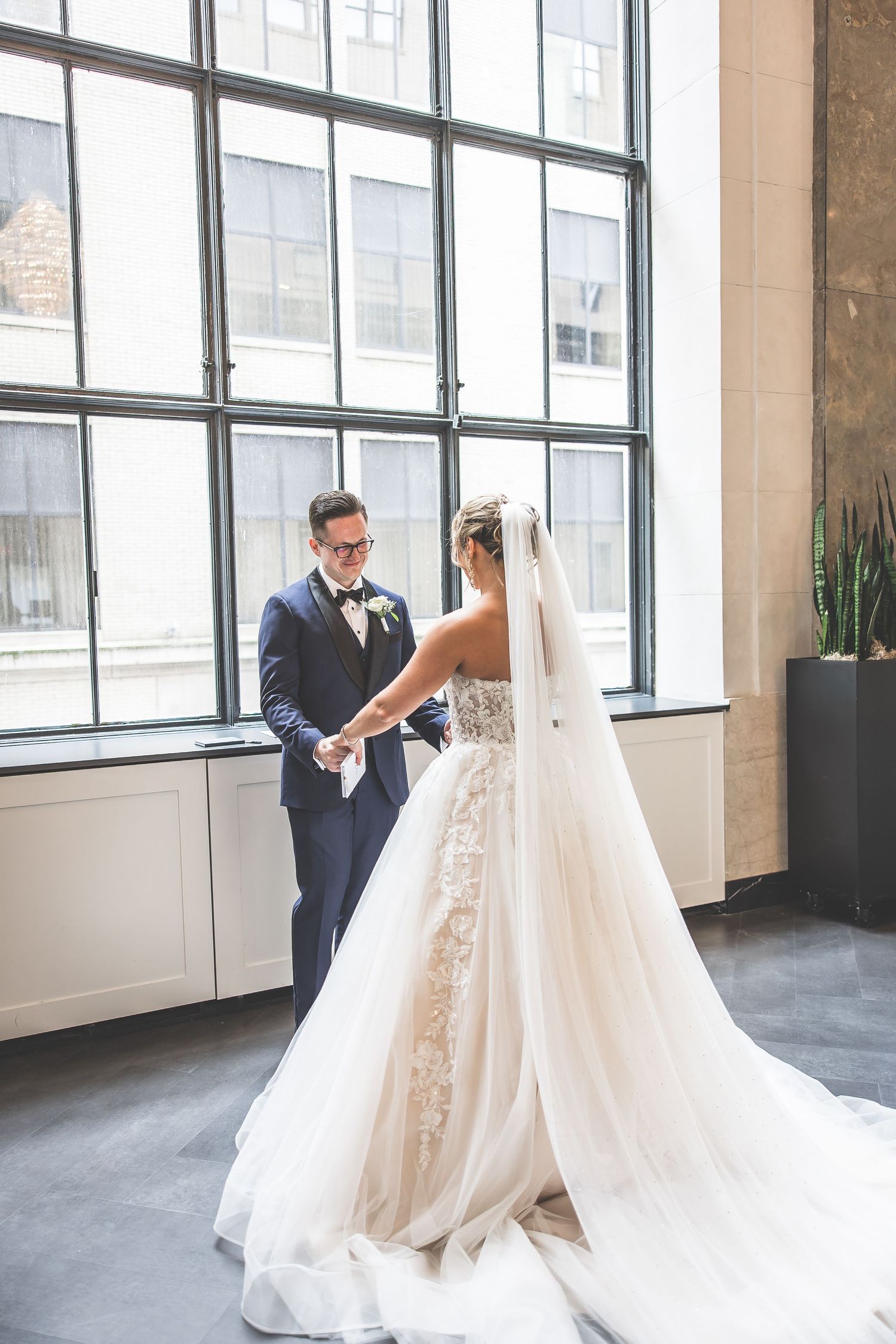 Wedding couple sharing their first look in a modern industrial venue with large windows.