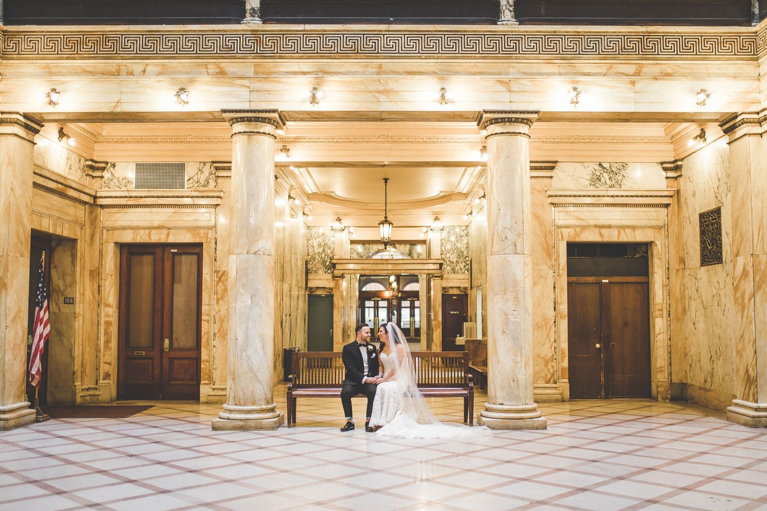 Grand ornate hallway with marble columns and decorative ceiling in historic building.