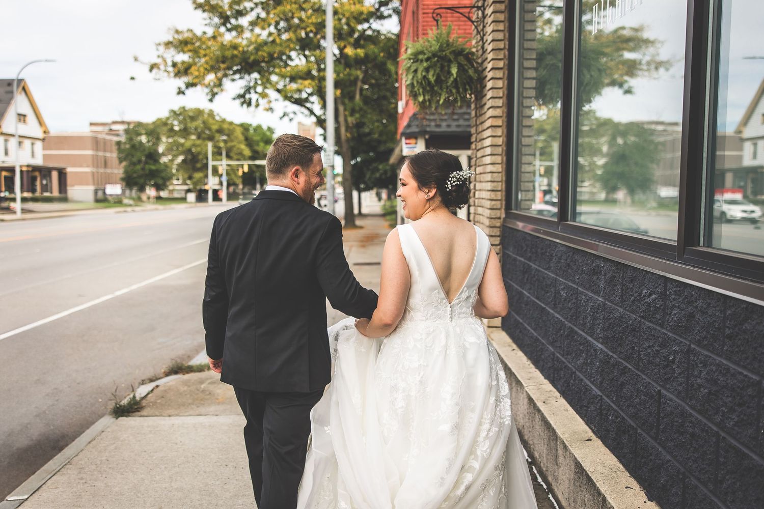 Couple walking together outside a modern building during their wedding photoshoot.
