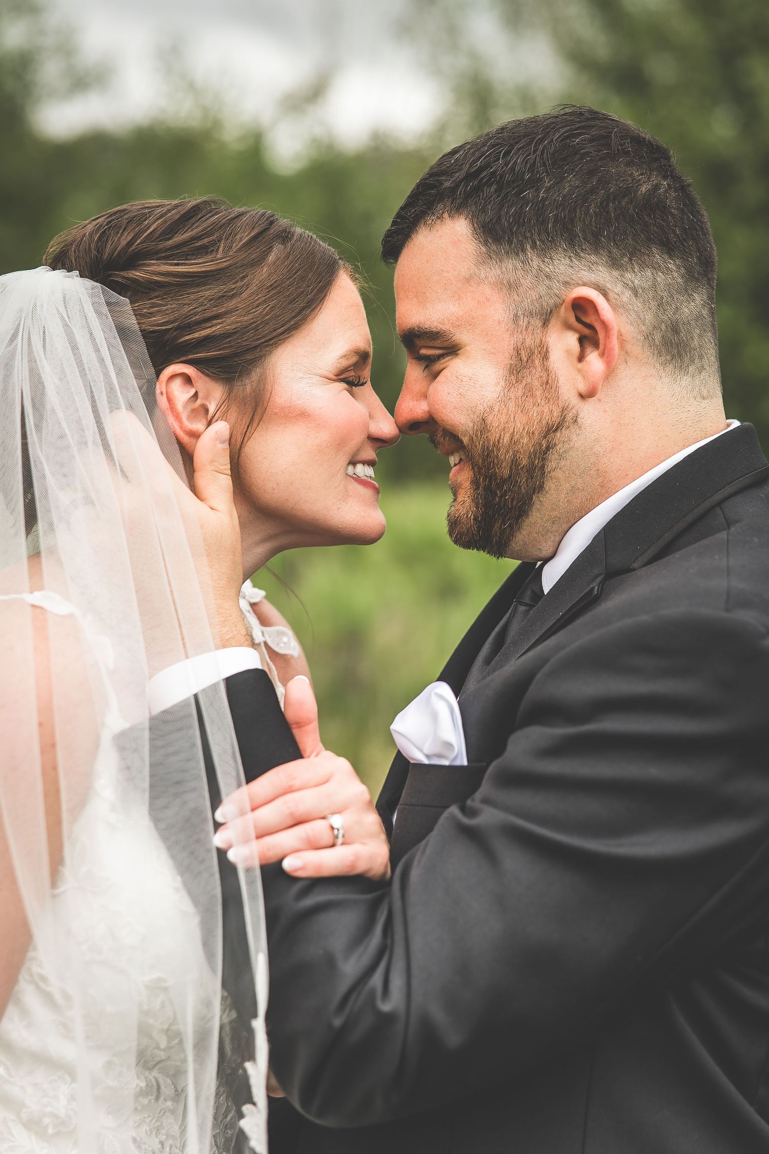 An intimate wedding portrait captures a tender moment between newlyweds against a soft natural backdrop.