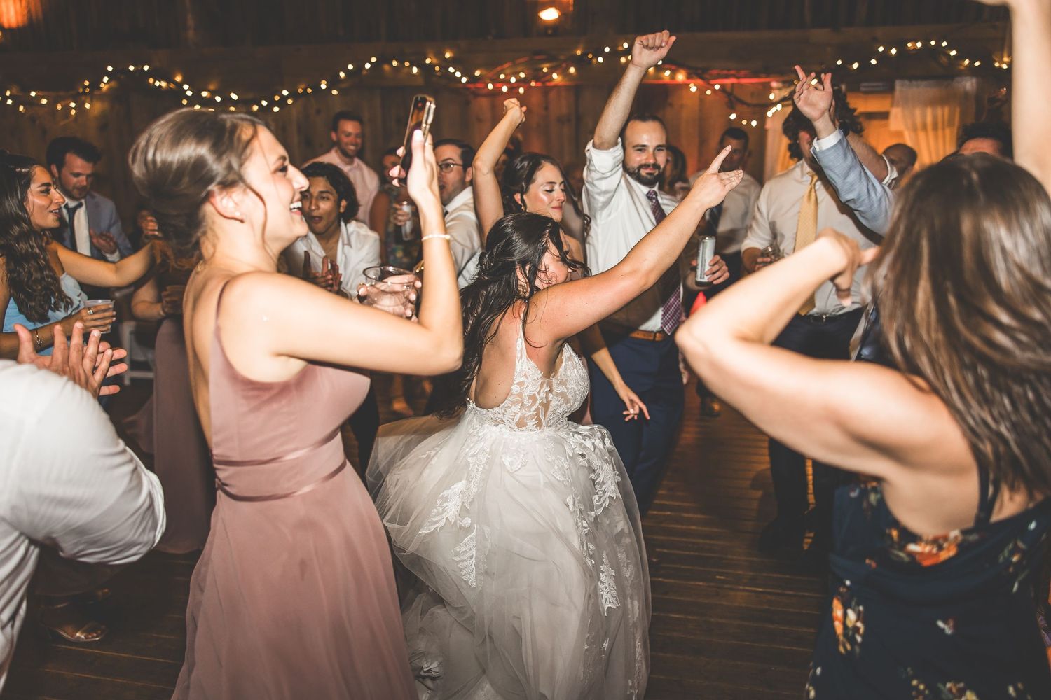 Crowded dance floor at a wedding reception with guests dancing under ambient lighting.
