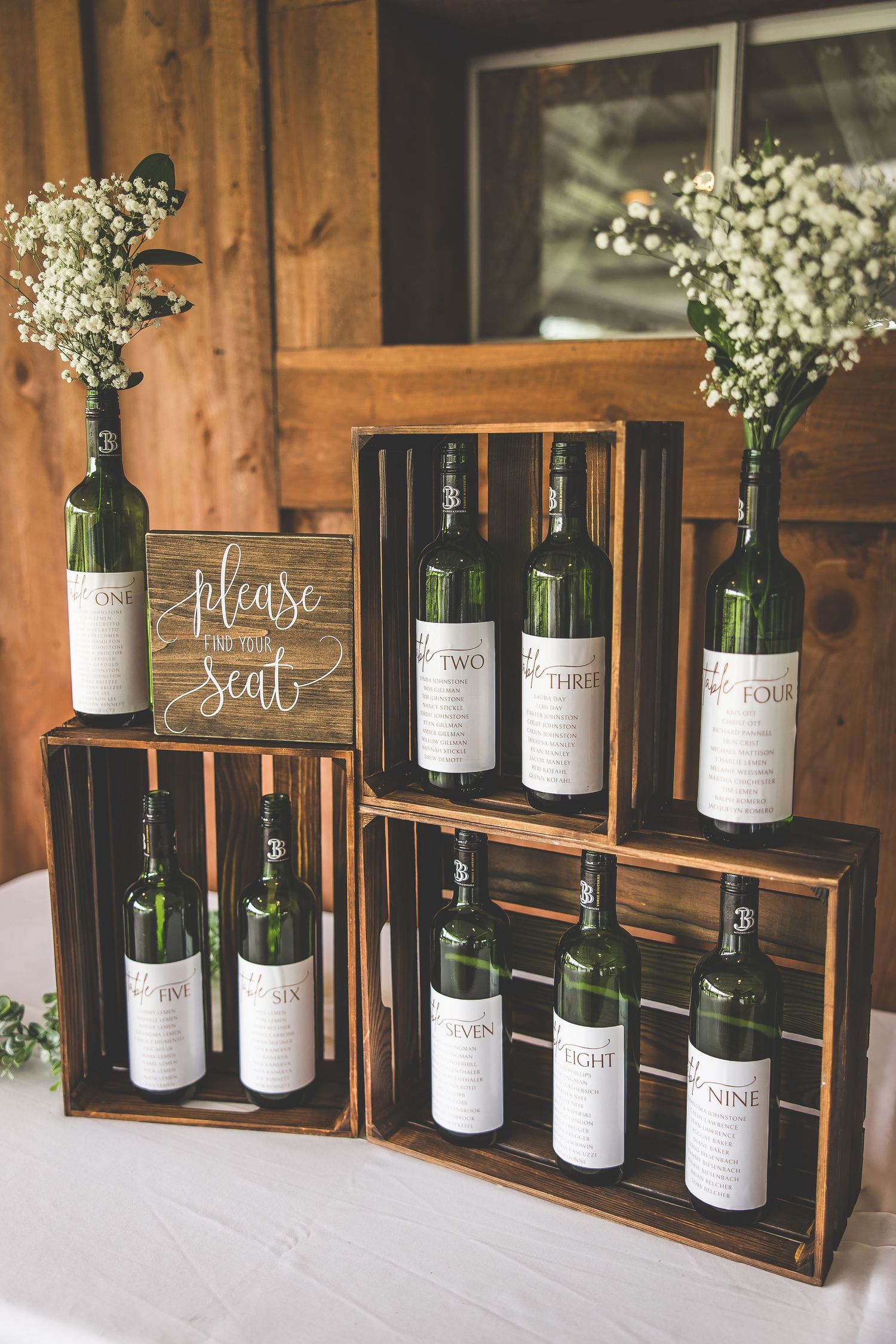 Wooden crate display of wine bottles with custom labels arranged as wedding decor.