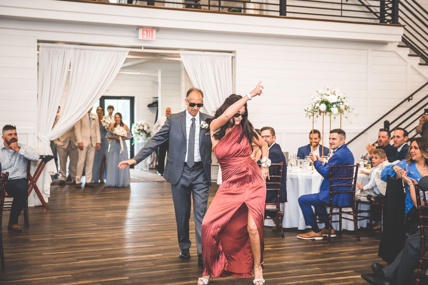 Wedding reception celebration with guests dancing in rustic indoor venue.