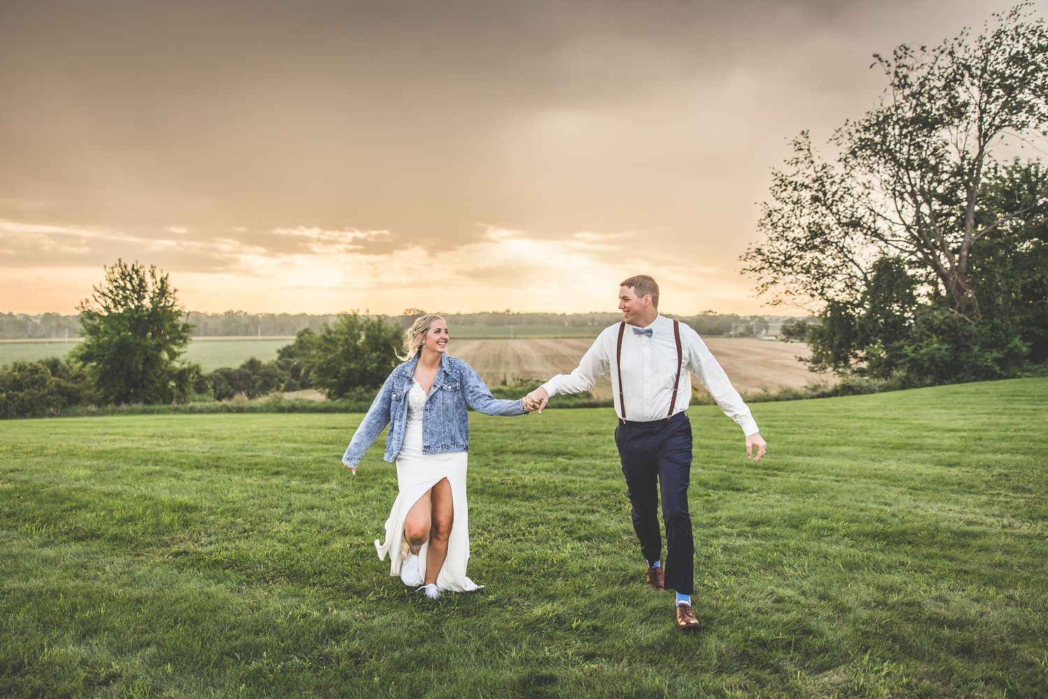 Casual engagement photos in a grassy field during golden hour.