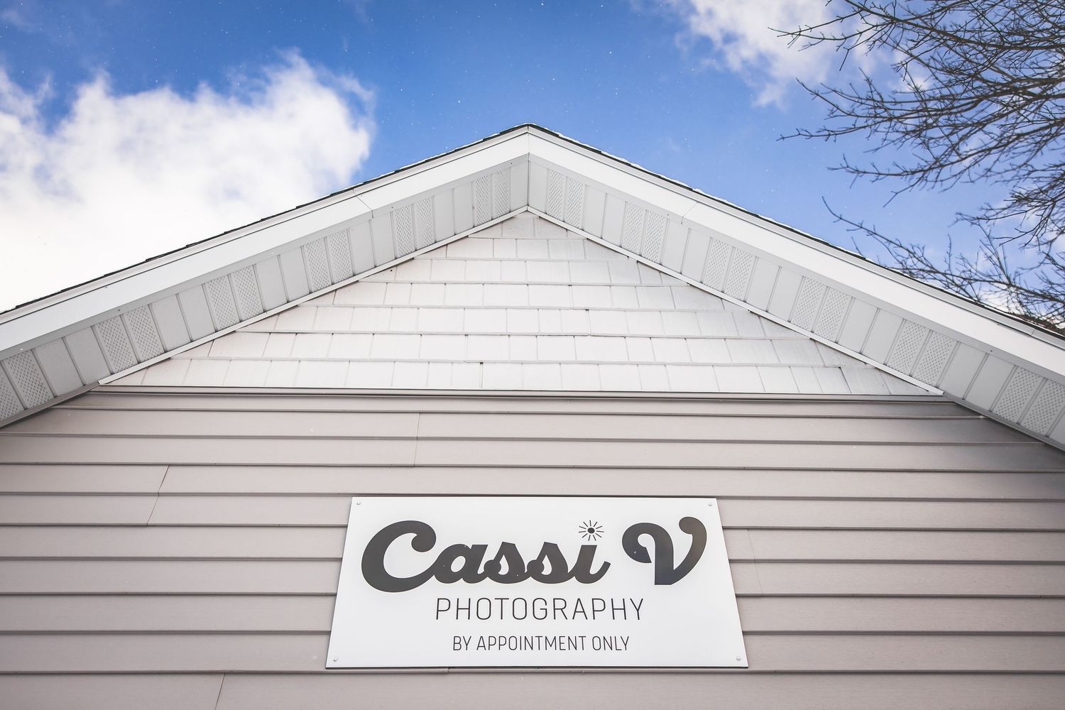 Row of white clapboard buildings with business signage under bright blue sky.