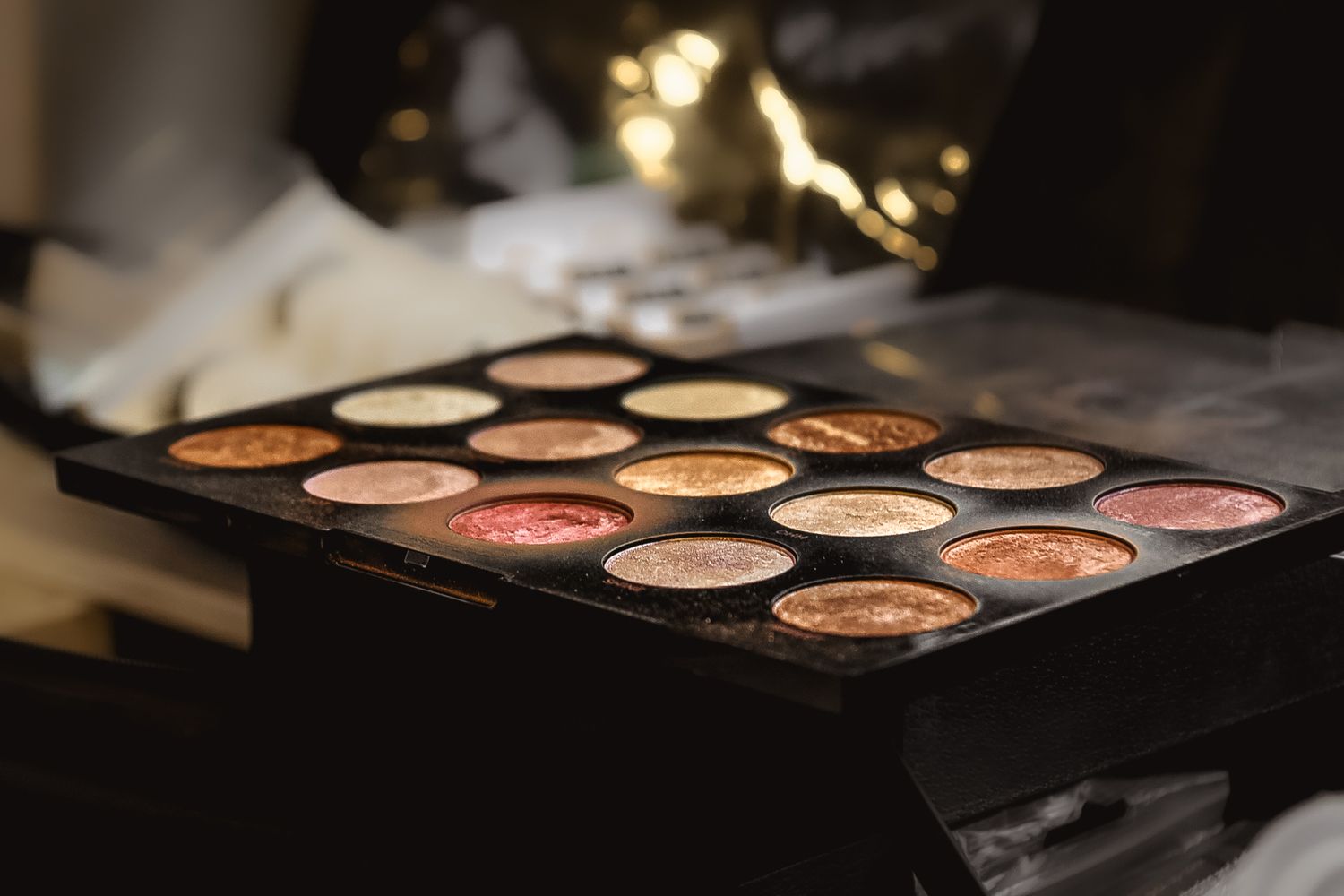 Professional makeup palettes and cosmetics arranged on dark surface with dramatic lighting.