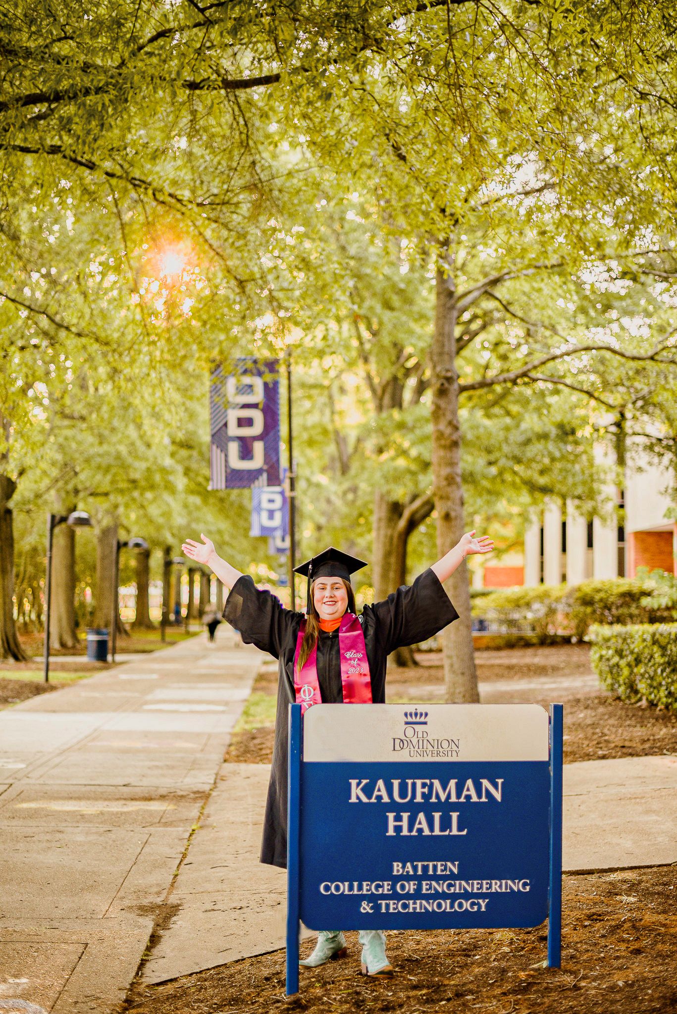 Graduation photos taken at Kaufman College of Engineering campus with signs and fall foliage.