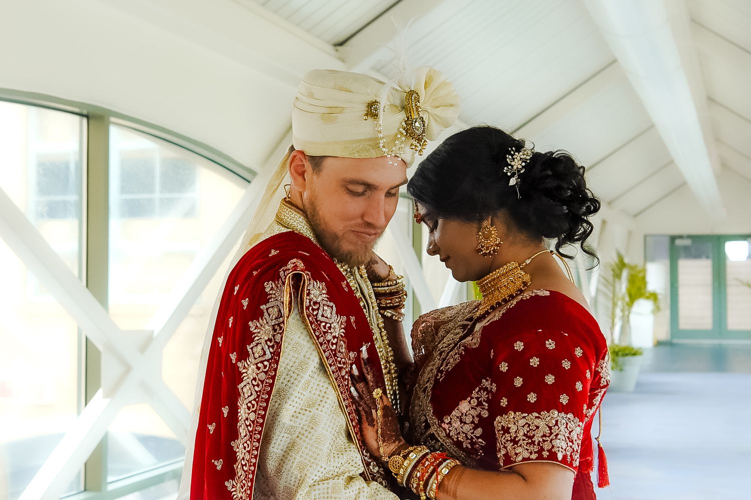 A couple in traditional Indian wedding attire share an intimate moment during their wedding ceremony.