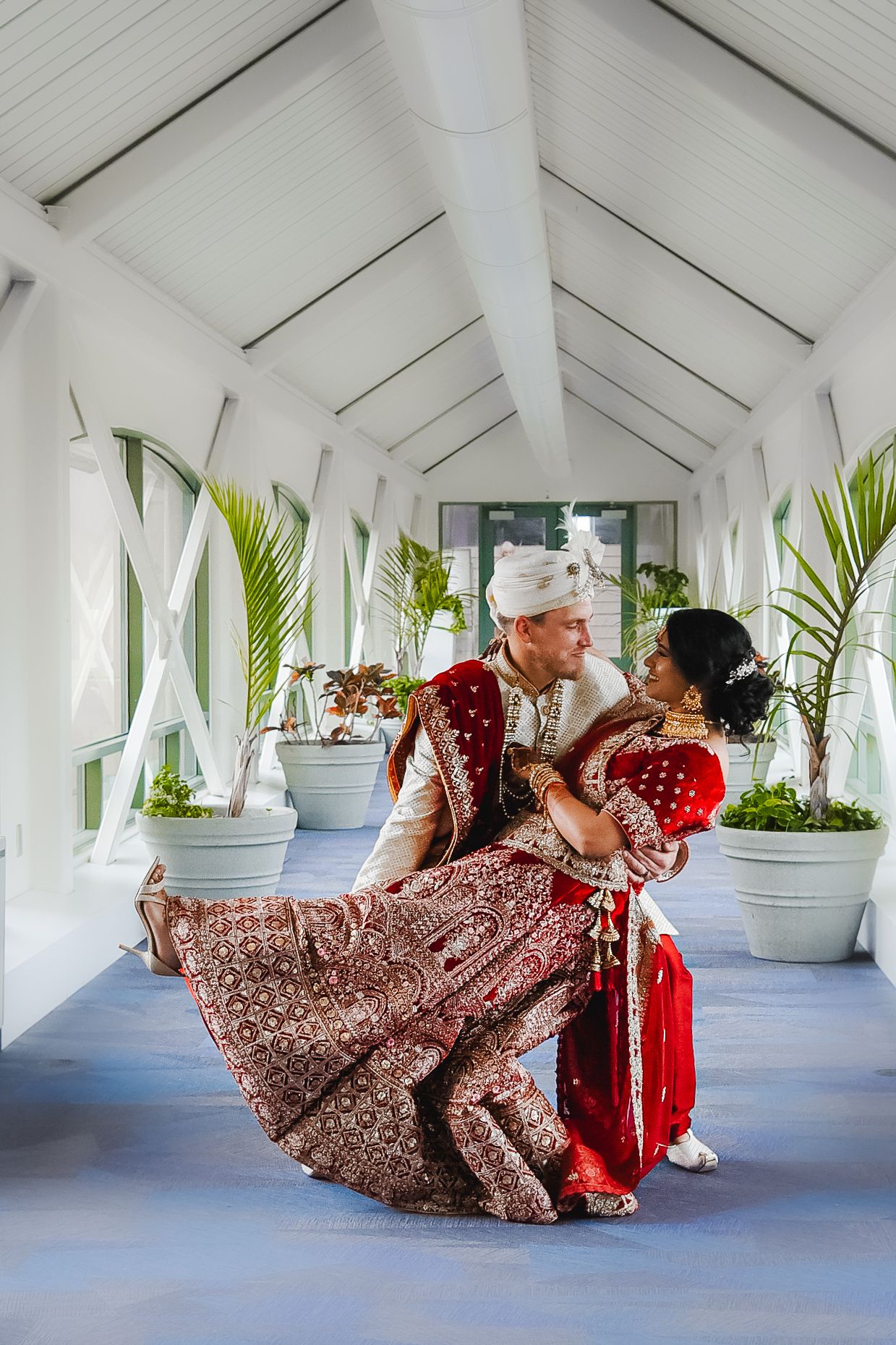 Traditional Indian wedding attire dance sequence in bright white hallway.