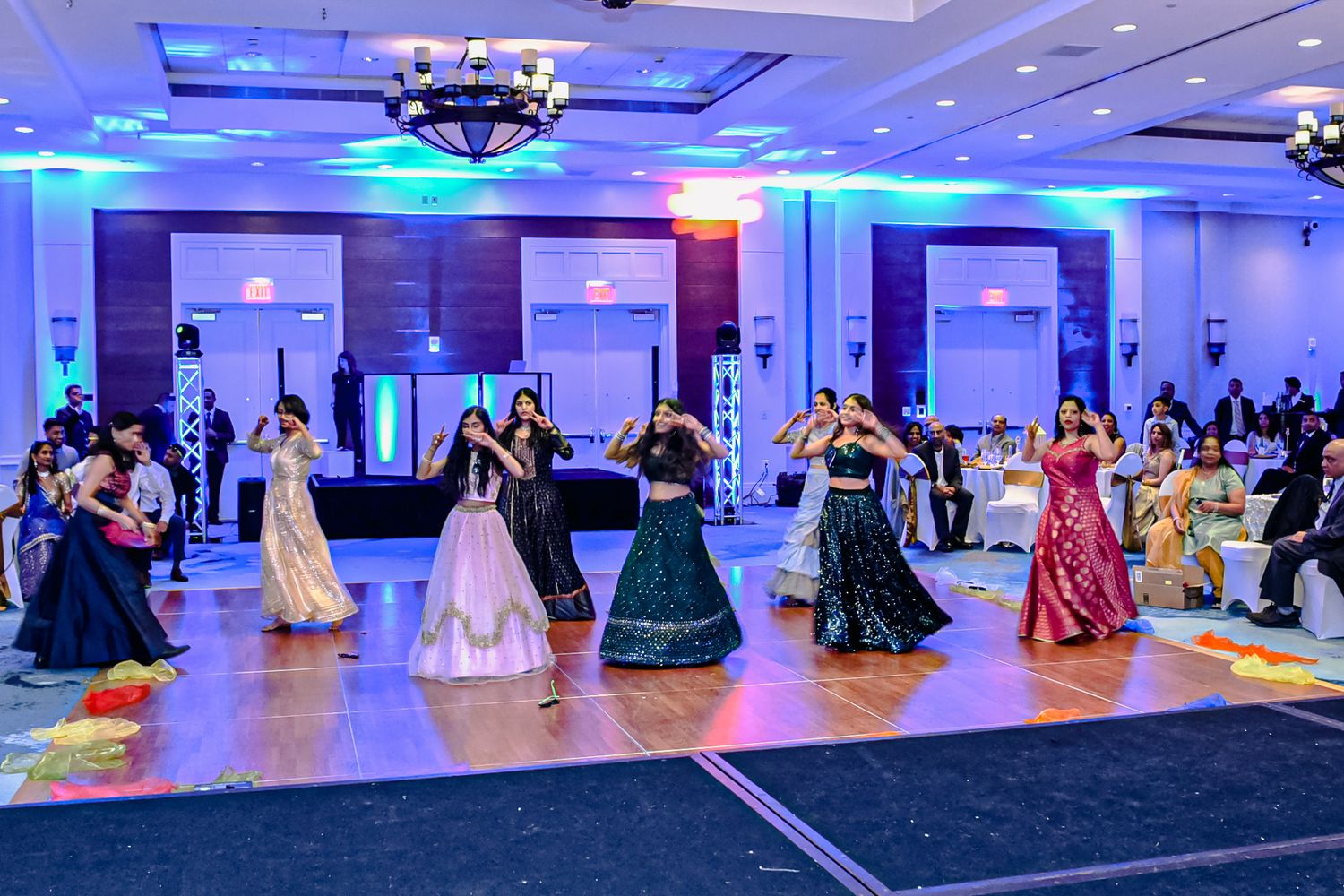 Elegant ballroom with blue uplighting and guests seated at round tables for a formal event.