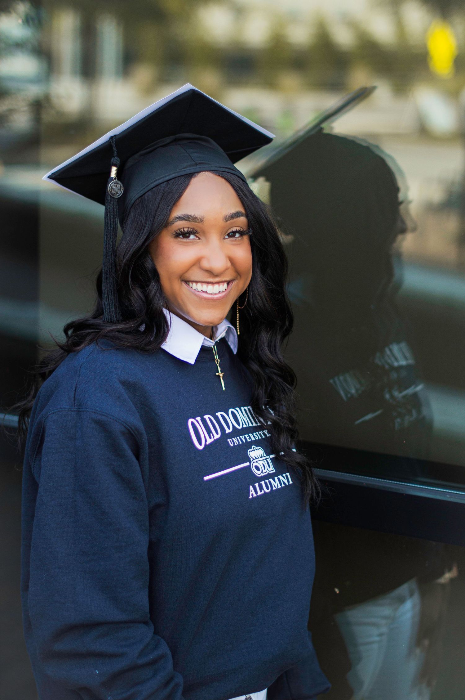 Graduate in navy blue cap and gown smiles during outdoor graduation photoshoot at Old Dominion University.