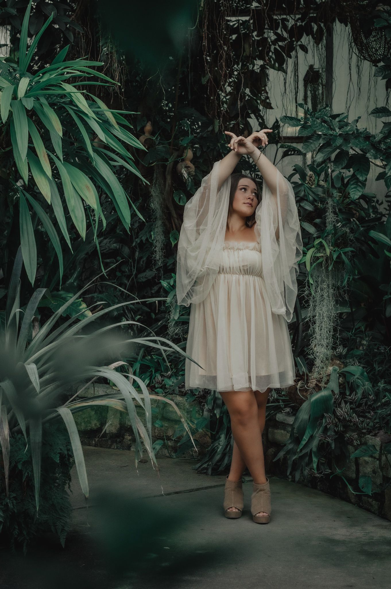 Artistic photos in flowy white dress surrounded by tropical plants and greenery.