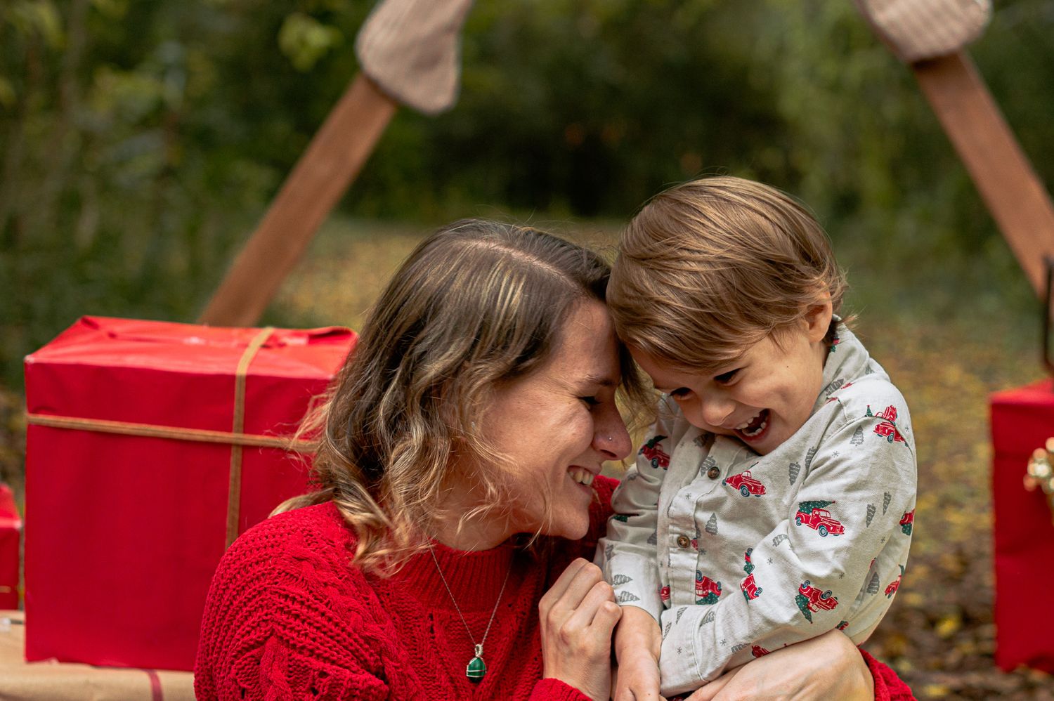 A heartwarming moment shared between parent and child wearing holiday outfits near red boxes.
