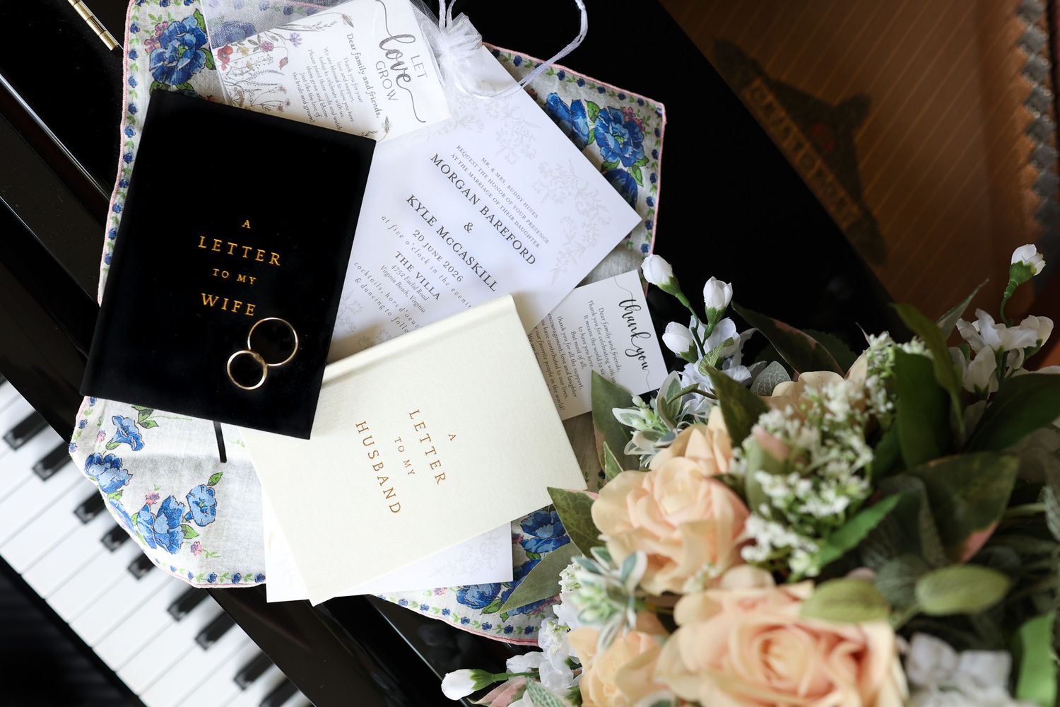 Wedding flat lay on piano keys featuring rings, bouquet, vows, and floral stationery for a romantic ceremony.