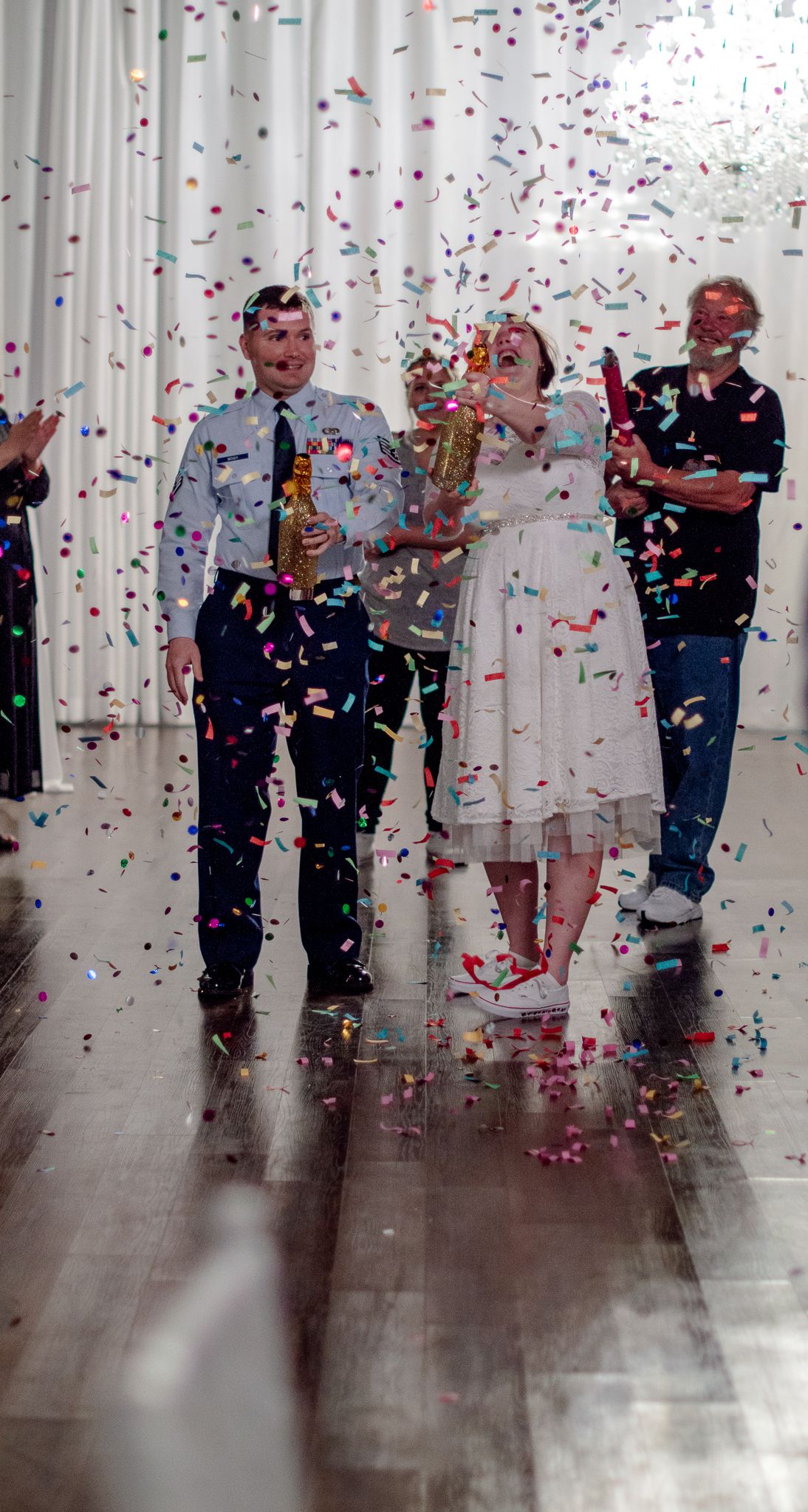Celebratory scene with confetti falling against white backdrop at formal event.