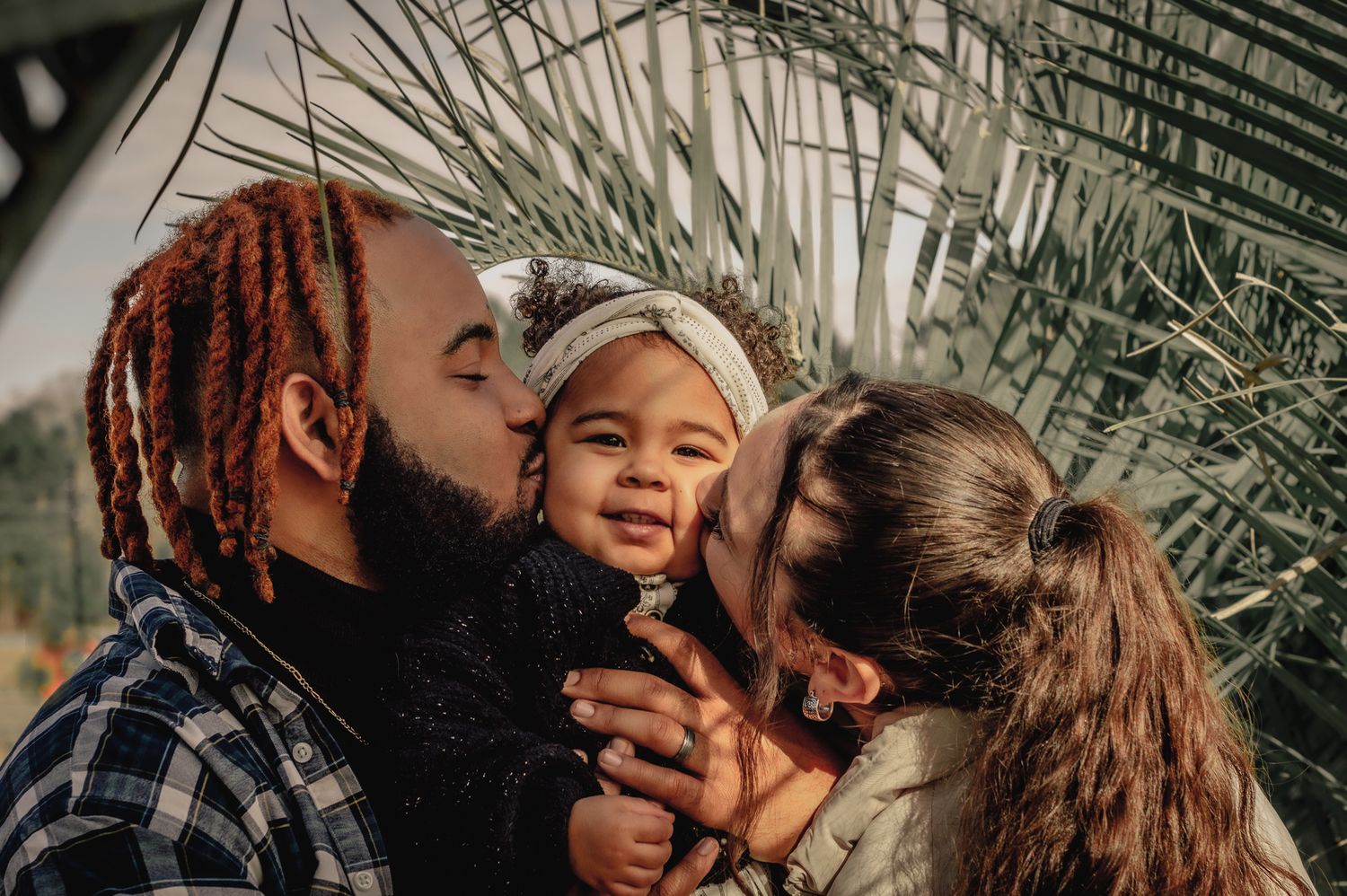 Tender moment between couple surrounded by palm fronds.