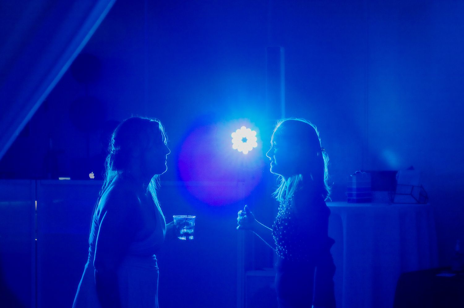 Silhouettes of party guests against deep blue lighting at an evening event.