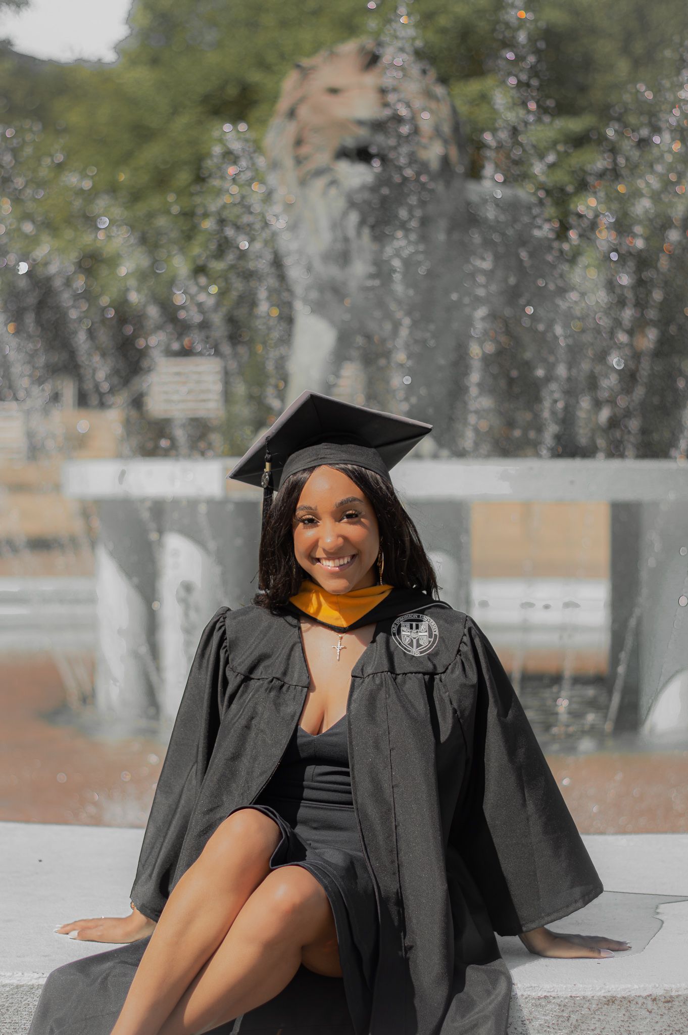 Graduate in cap and gown poses joyfully outdoors during commencement celebration.