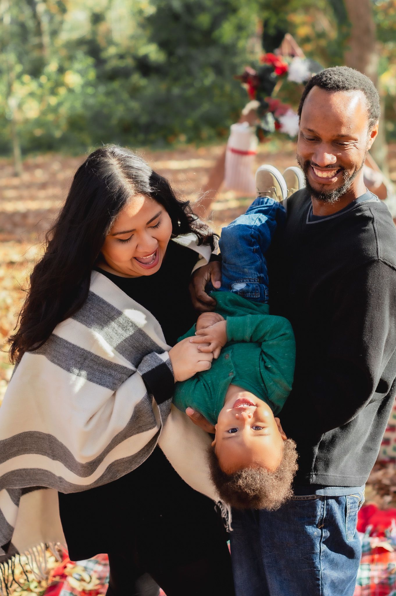 Happy family playing and laughing together during outdoor autumn photoshoot.
