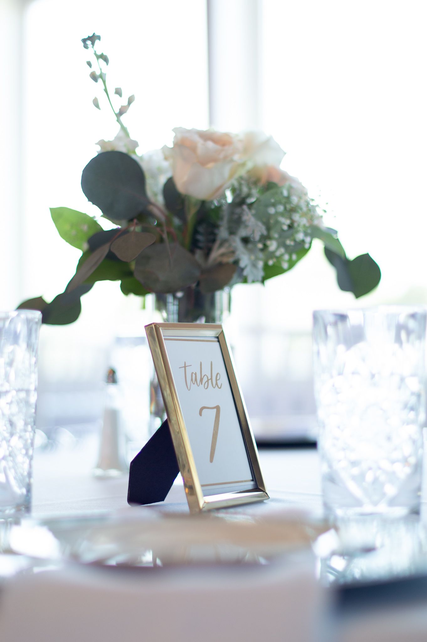 Elegant table setting with floral centerpiece and gold-framed table number.