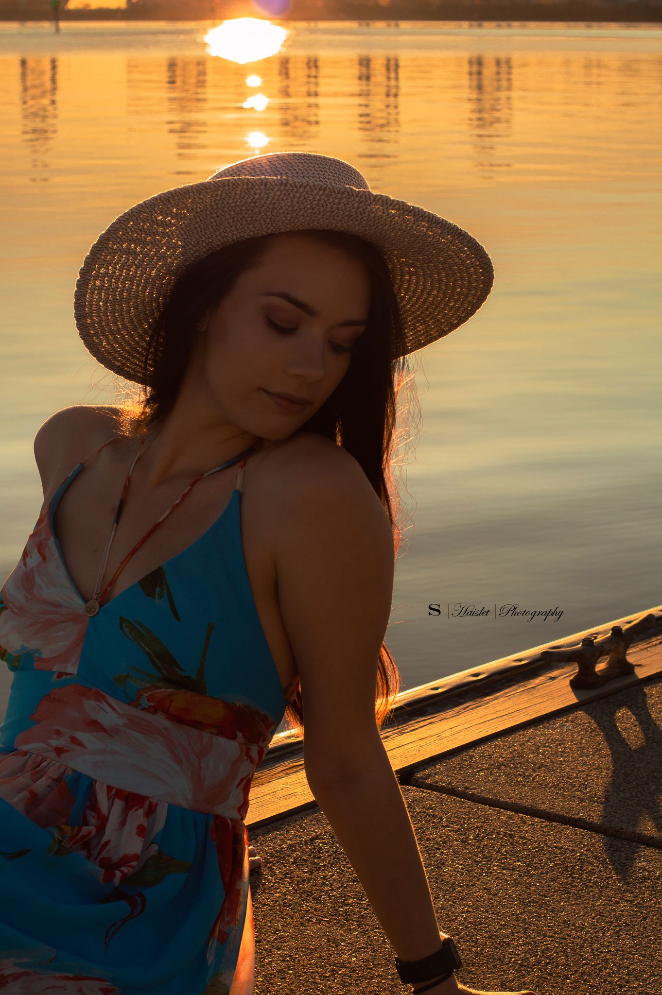 Artistic sunset portraits at lakeside with person in blue dress and straw hat.