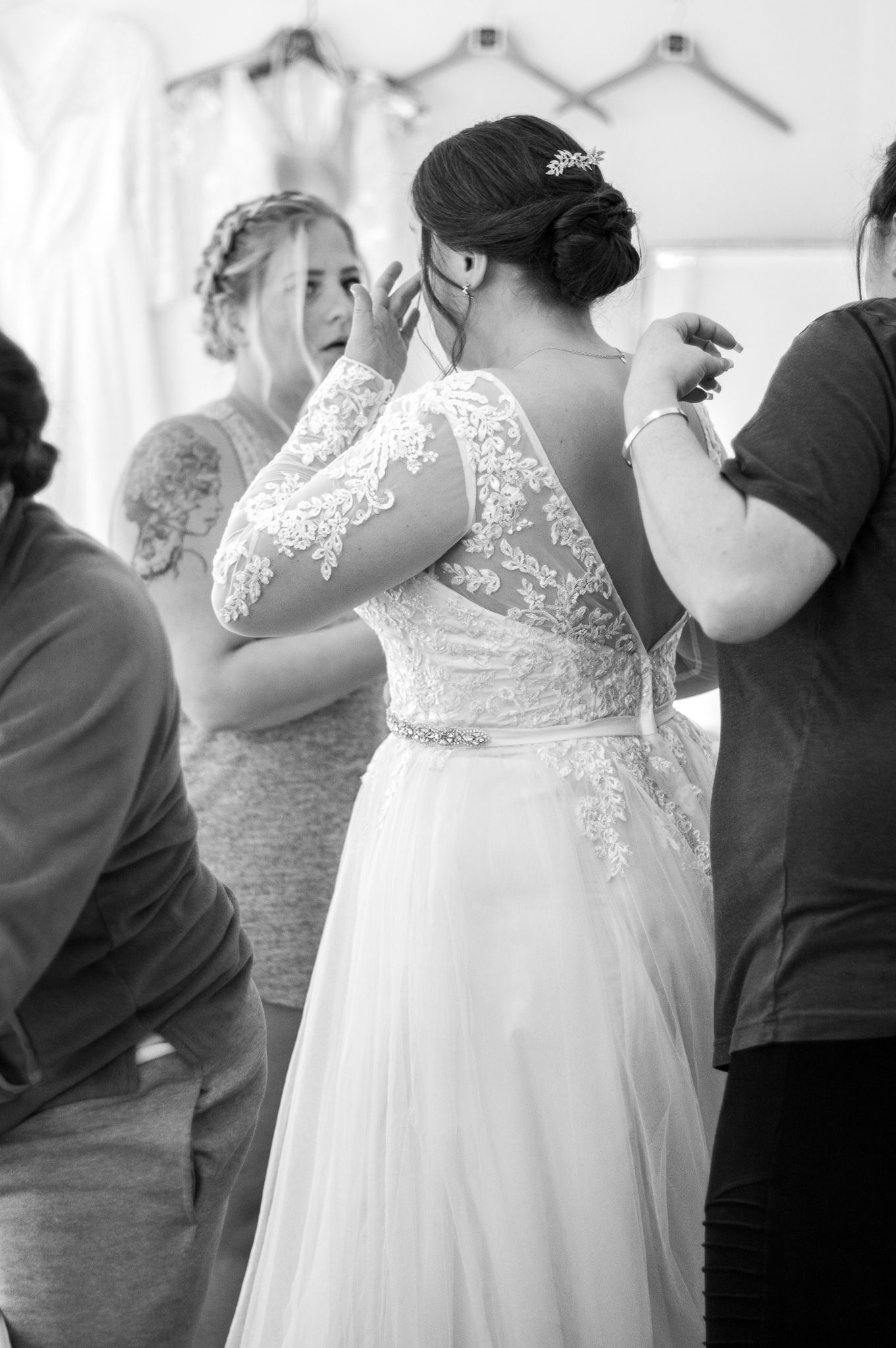 Black and white candid photo of a bride in a lace wedding dress dancing and laughing at a reception celebration.