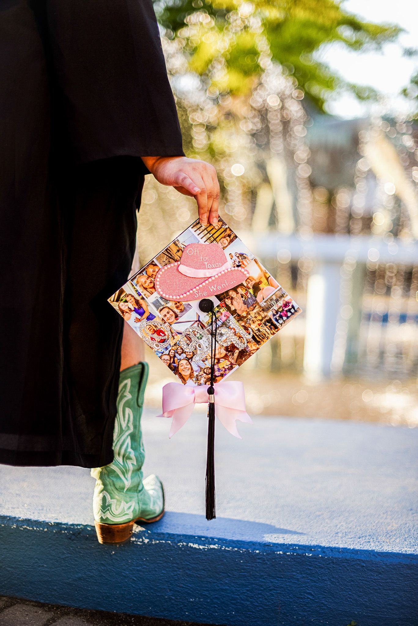 Close-up of graduation cap decorated with pink and floral designs next to cowboy boots.