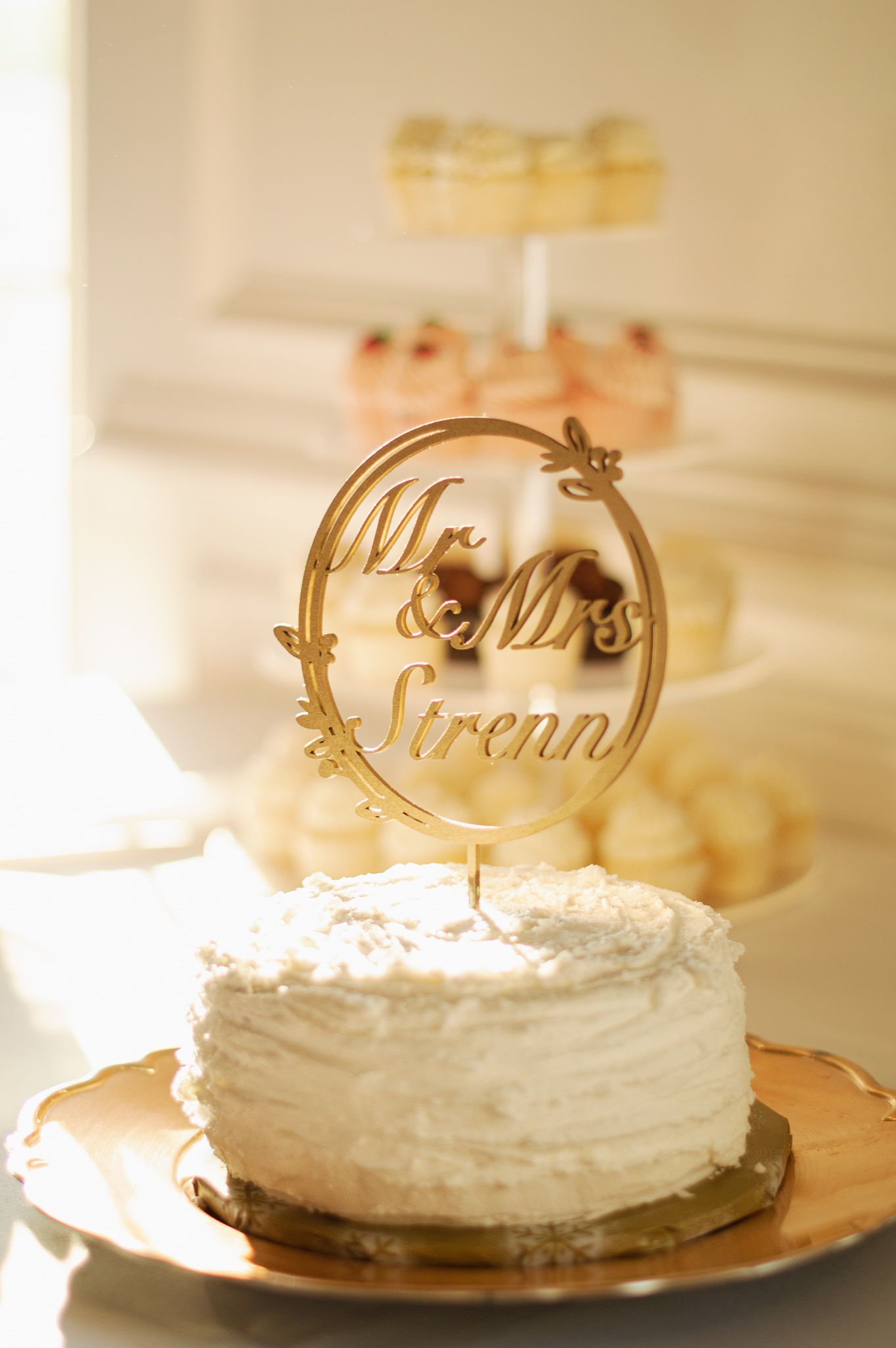 White wedding cake with gold 'Mr & Mrs' topper decoration in elegant presentation.