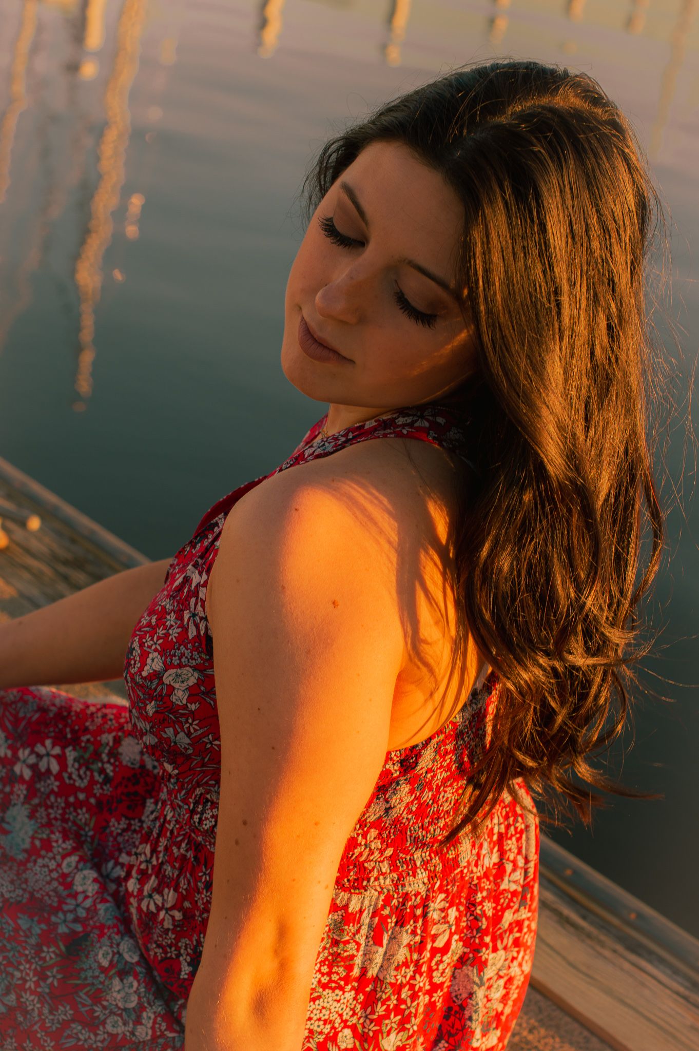 Sunset beach portrait featuring person in red floral dress with warm golden lighting.