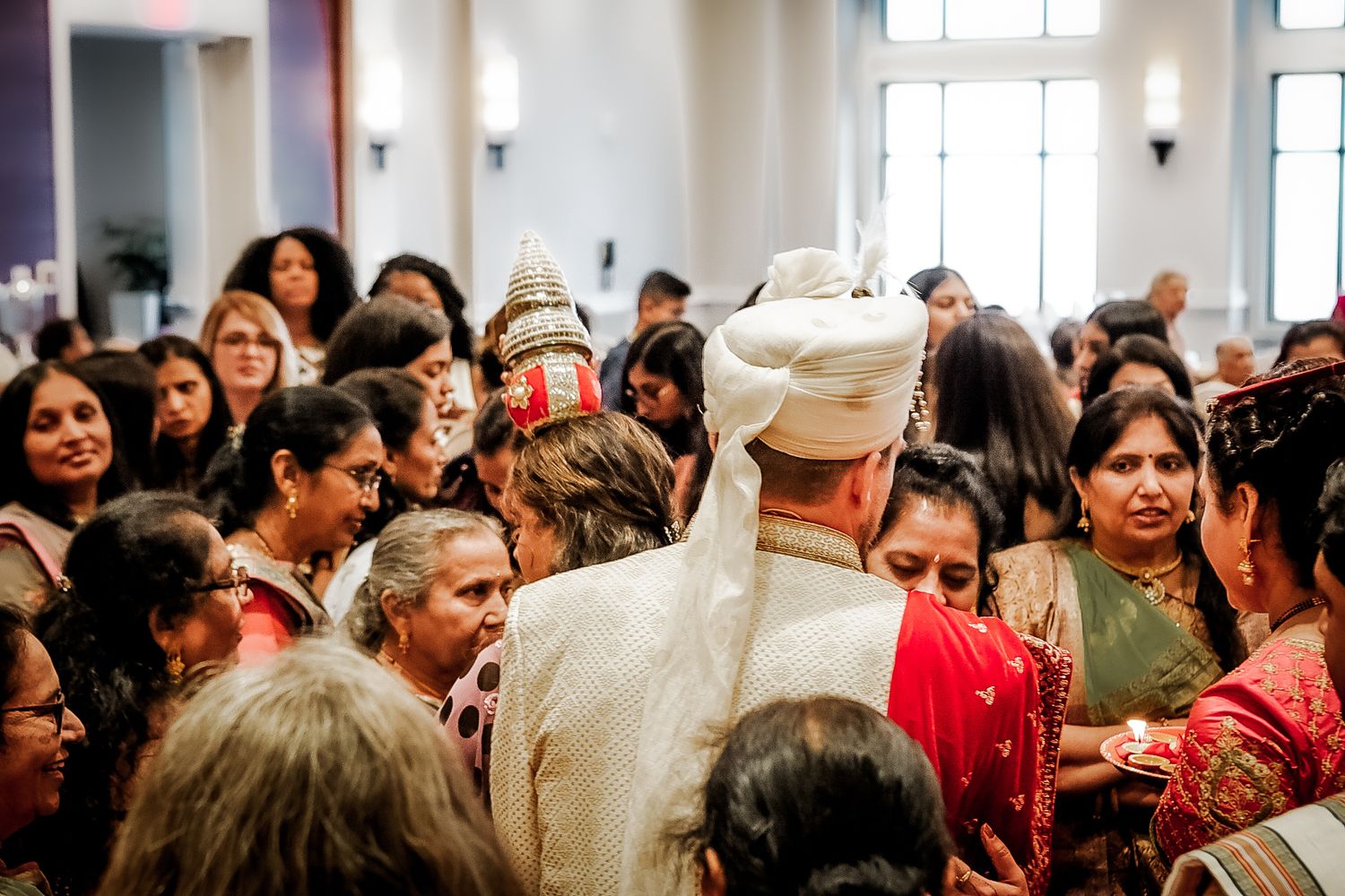 A crowded indoor celebration with guests mingling in formal attire.