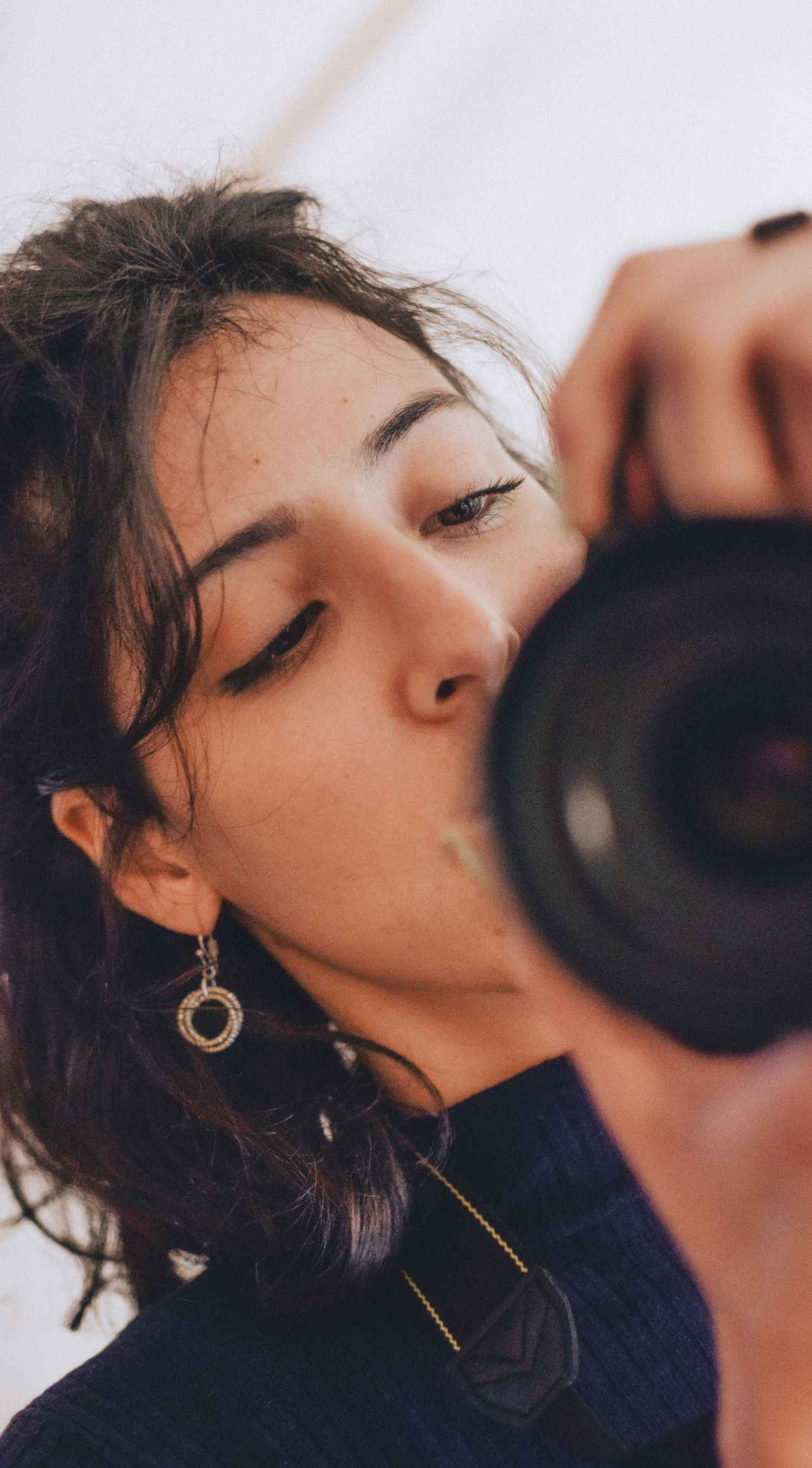 Close-up of wedding photographer with a camera while wearing circular gold earrings and a dark top.