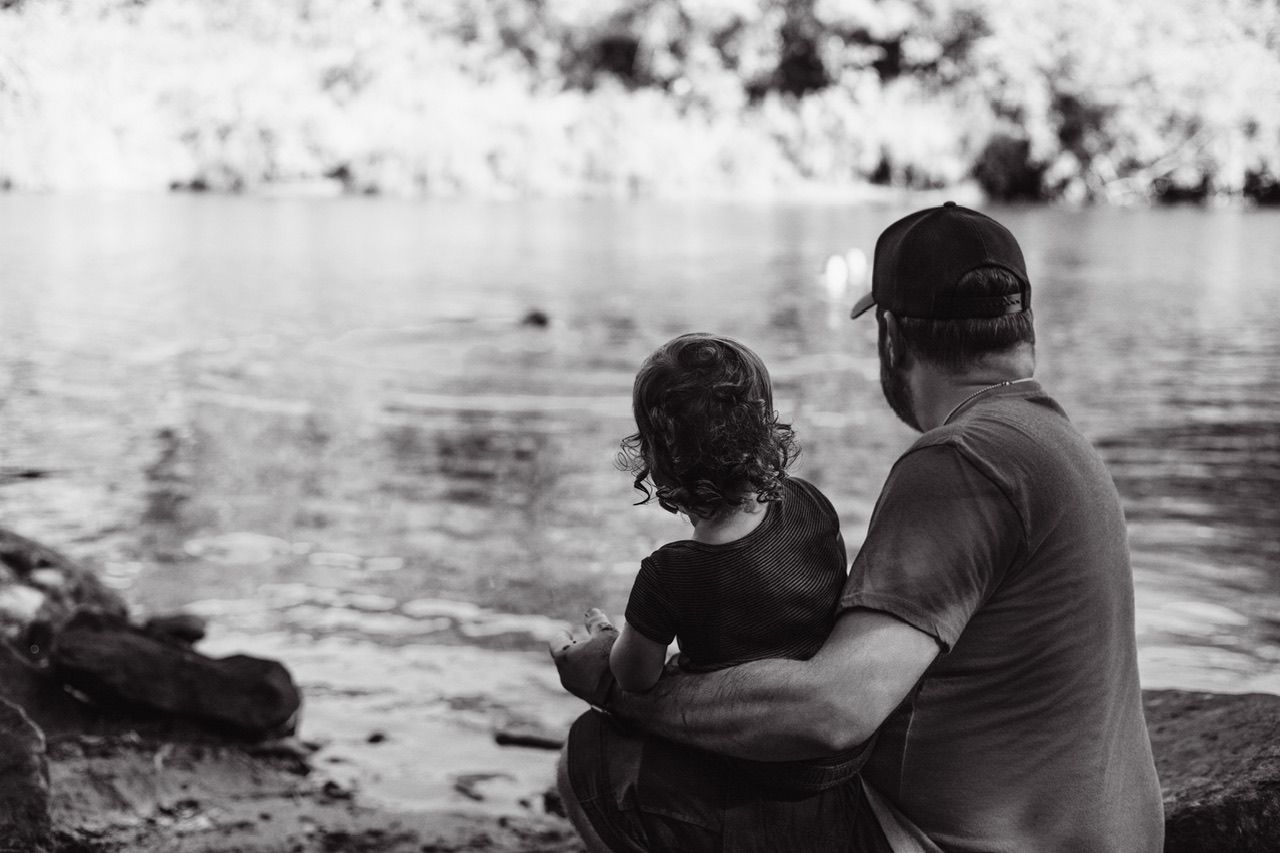 Black and white silhouette of family bonding by the water's edge.