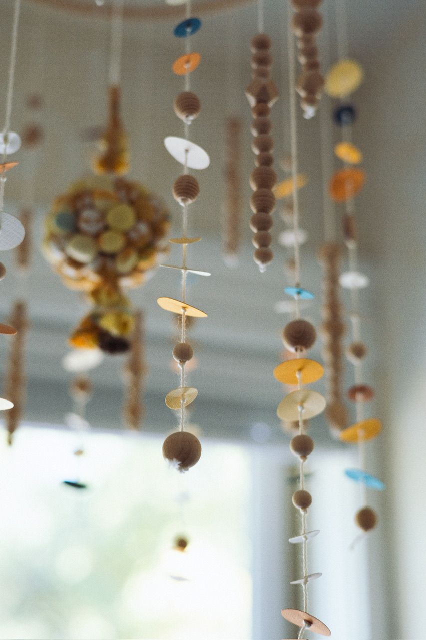 Decorative hanging mobile with wooden beads and shapes creating a whimsical ceiling display.