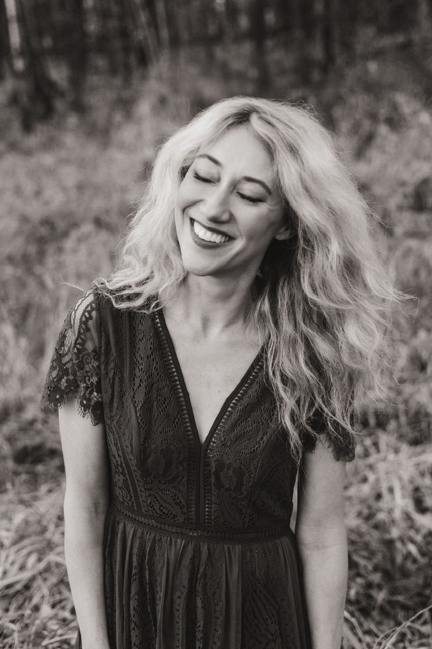 Candid black and white portrait showing carefree laughter in a lace dress.