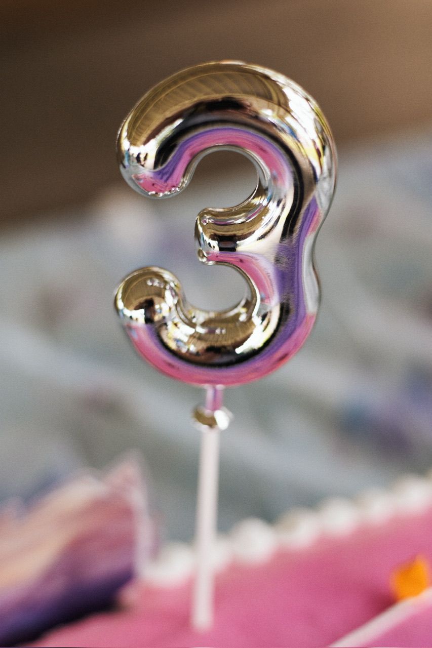 Metallic pink and gold number 3 balloon decoration photographed in macro detail.
