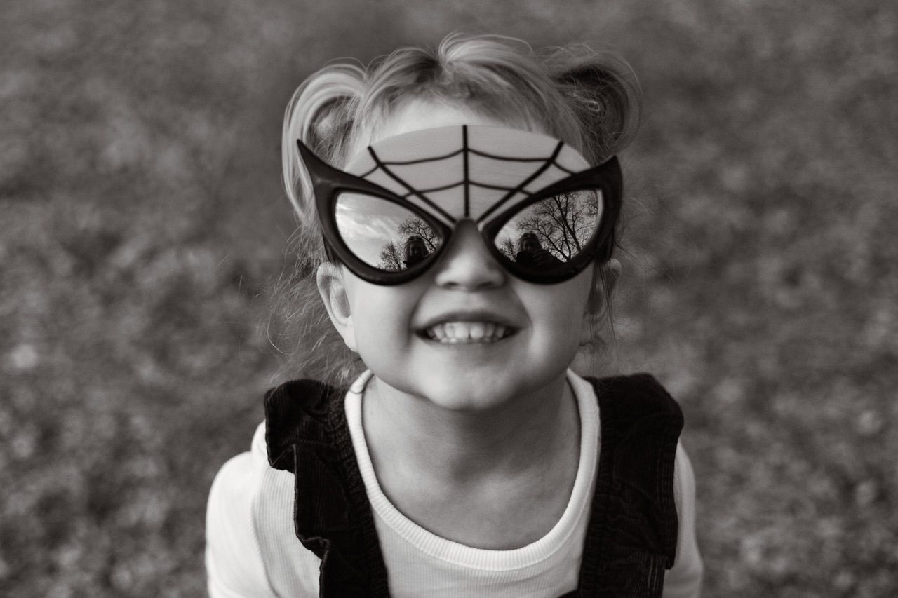 Black and white sequence showing child wearing fun costume accessories and making silly faces.