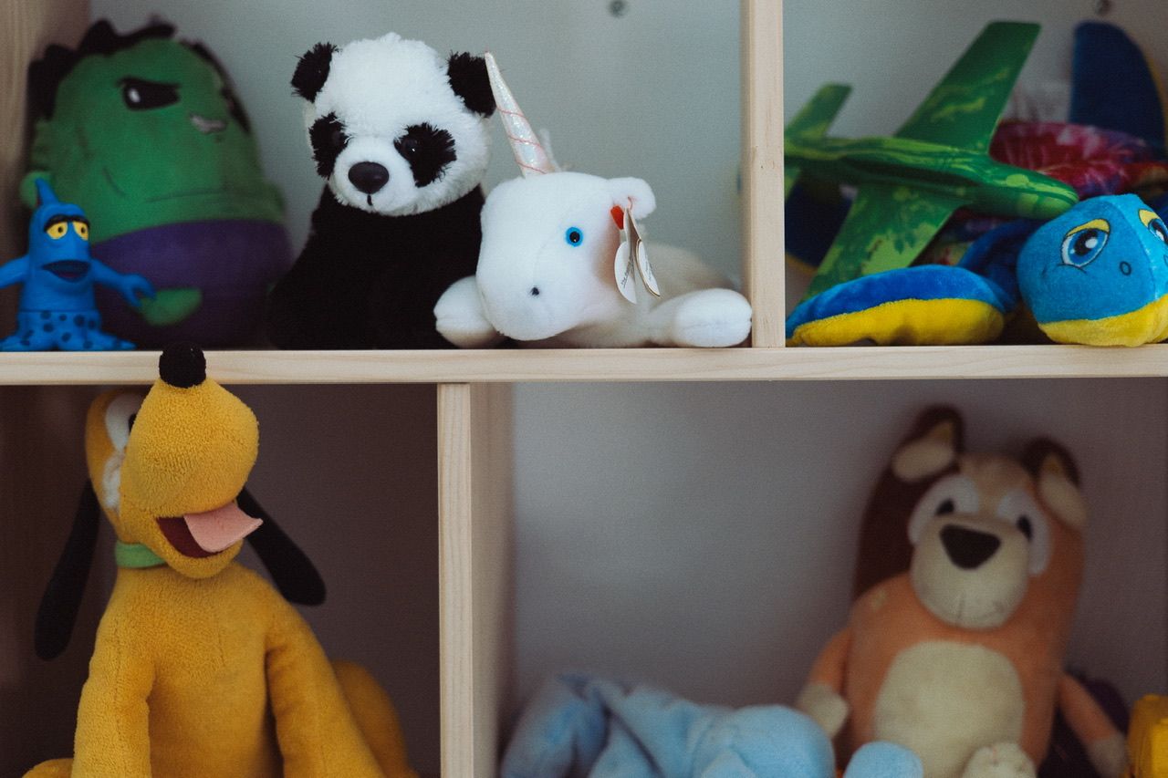 Colorful stuffed animals including pandas and plush toys arranged on shelving.
