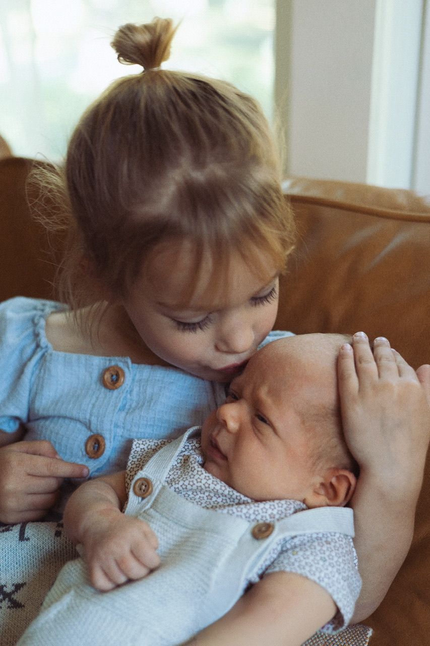 A tender sequence of siblings sharing gentle moments together on a brown leather couch.