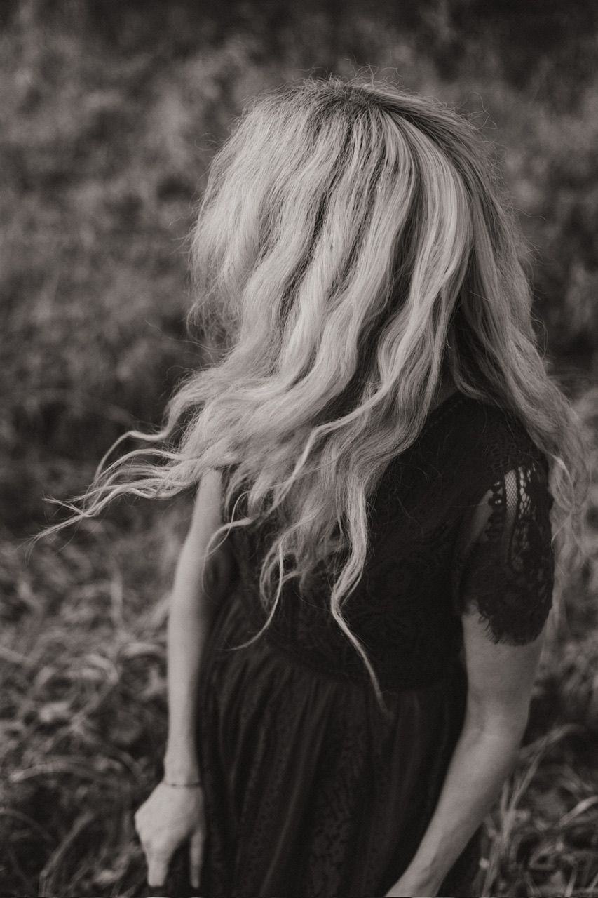 Dramatic black and white close-up of flowing blonde hair and lace dress details.