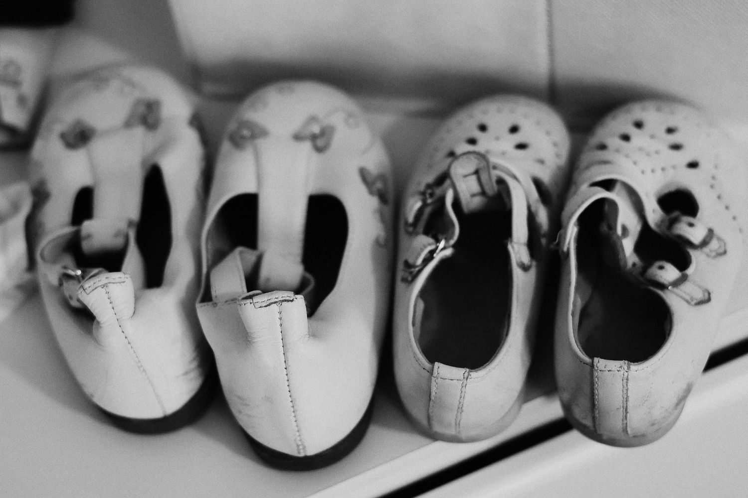 Row of vintage baby shoes arranged in black and white.