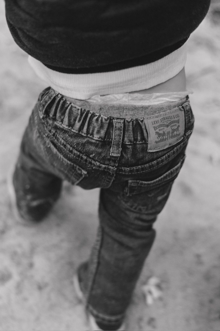 Low angle view of someone wearing loose-fitting jeans and a white shirt.