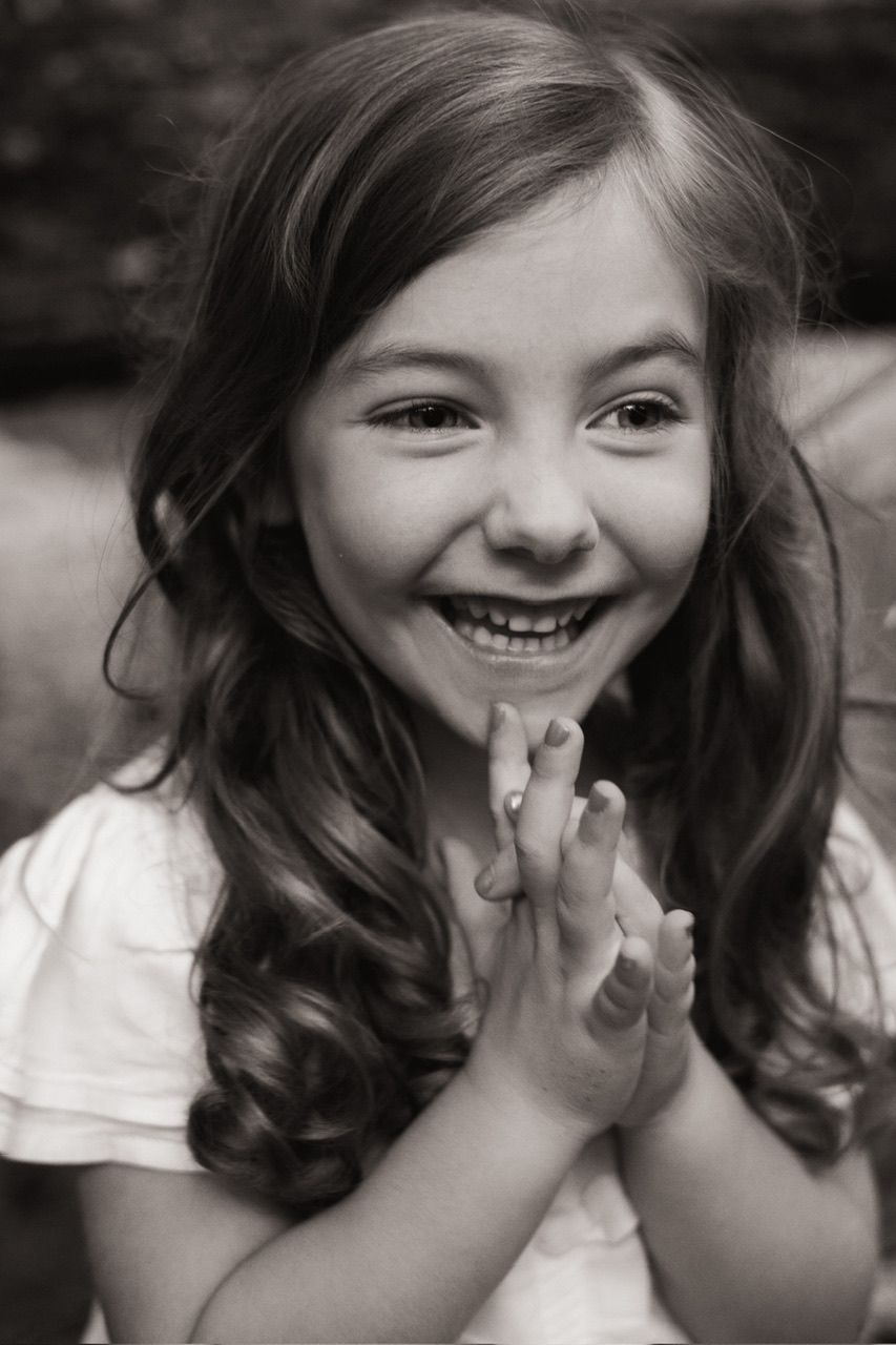Black and white portrait of a young child with curly hair expressing pure delight and happiness.
