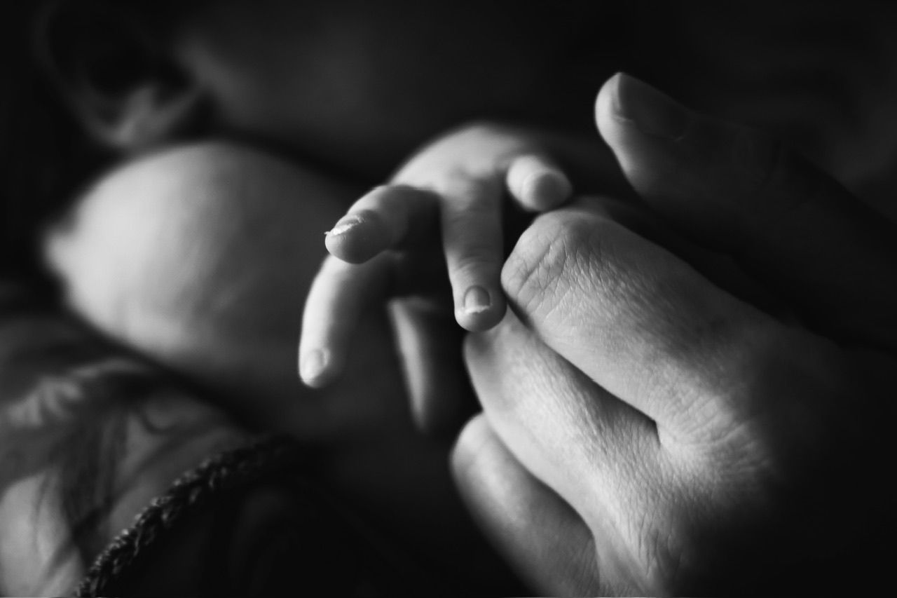 Close-up black and white photo of intertwined hands showing connection and intimacy.